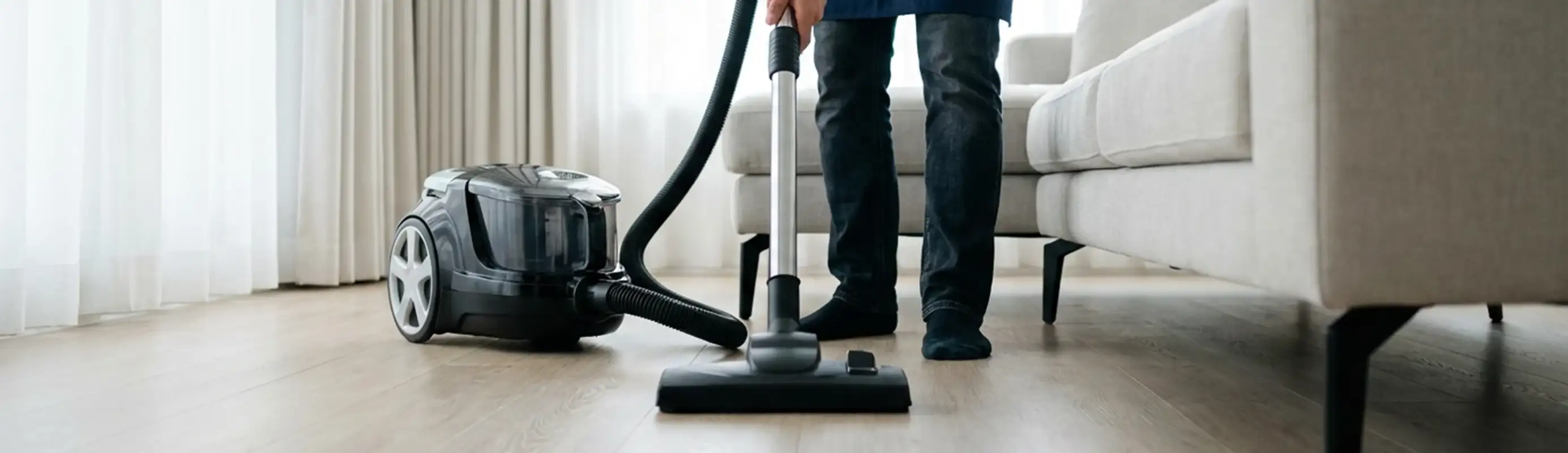 Professional house cleaner vacuuming a living room floor with a canister vacuum cleaner, Duluth, MN.