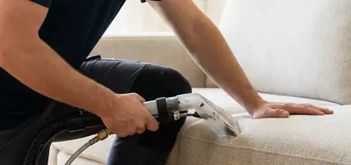 Professional upholstery cleaner deep-cleaning a fabric sofa with a handheld extraction tool, Duluth, MN.